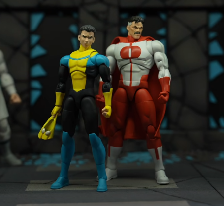 Jada Toys Invincible Mark Grayson in his original yellow, black, and blue costume with unmasked head, next to Omni-Man